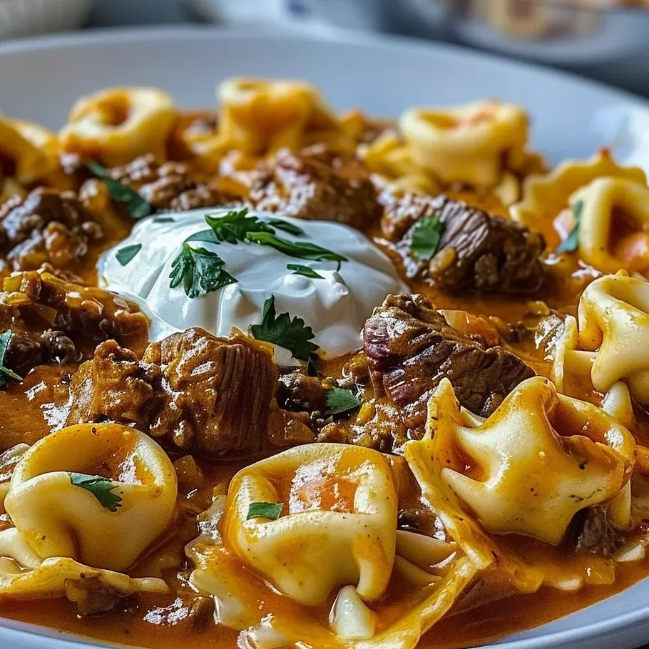 Un plato con tortellini de carne enchilada con queso.