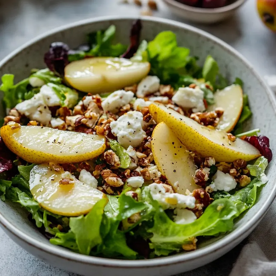 Un bol de ensalada con pera, queso feta y lechuga.