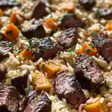 Un sartén con arroz, carne y verduras.
