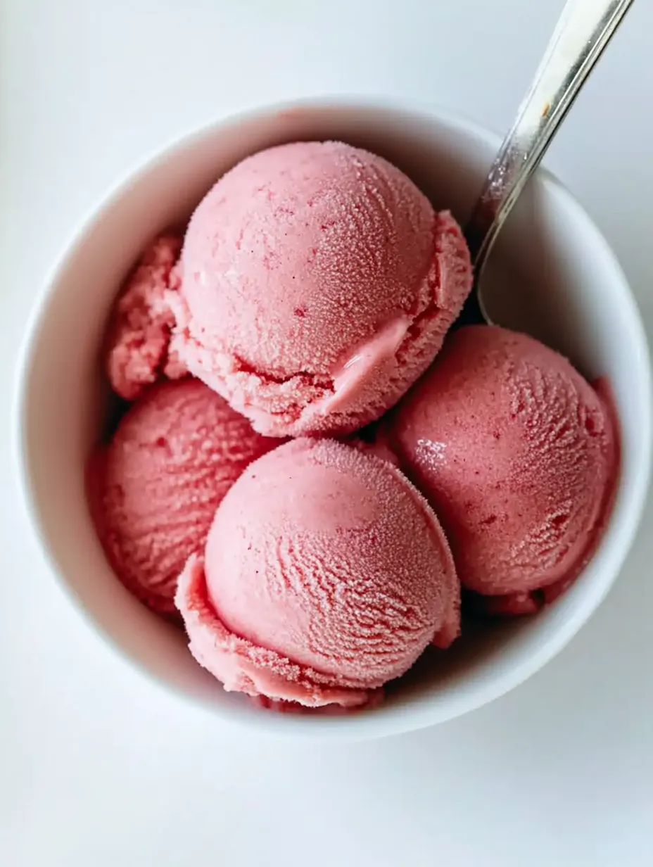 Un bol de yogur helado rosa con una cuchara dentro.