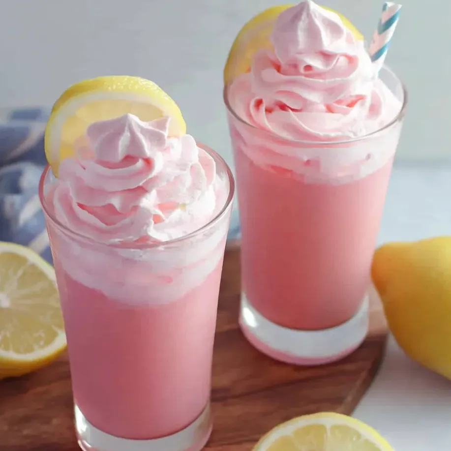 Dos vasos de limonada rosa con rodajas de limón sobre la mesa.