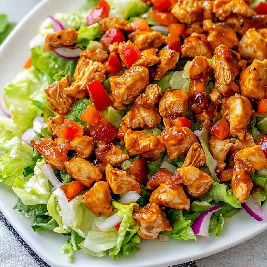 Un plato de ensalada de pollo con lechuga y tomates.