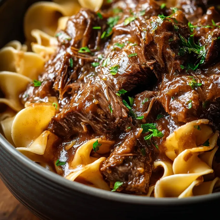 Un plato de pasta con carne y salsa.