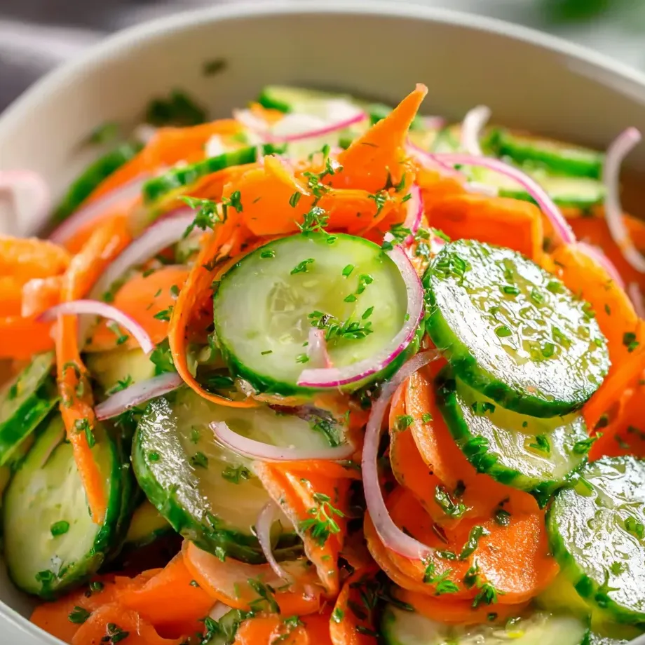 Un tazón lleno de verduras como zanahorias, pepinos y cebolla.