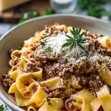 Un plato de pasta con salsa de carne y queso.