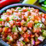 Un tazón de pico de gallo con jitomate, cebolla y chile.