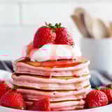 Una torre de panqueques con fresas arriba.