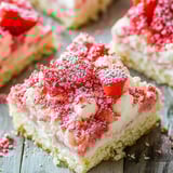 Una porción de pastel con frosting blanco y fresas encima.