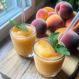 Dos vasos de jugo de melocotón con hojas de menta.