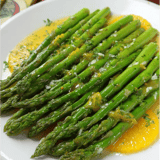 Un plato de espárragos con salsa.