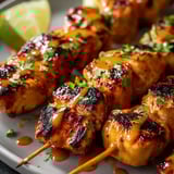 Un plato de brochetas con salsa encima.