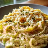 Un plato de pasta con queso y hierbas.