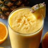 Un vaso con trozos de ananas arriba y naranja.
