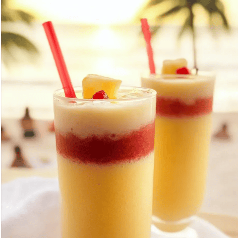 Dos vasos con jugo de piña y popotes rojos.