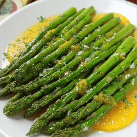 Un plato de espárragos con salsa.