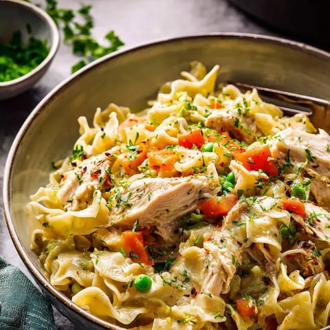 Un plato de pasta con pollo y verduras.