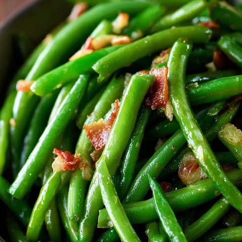 Un plato de judías verdes con trozos de tocino.
