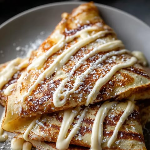 Un plato lleno de panqueques untados con mantequilla y azúcar.
