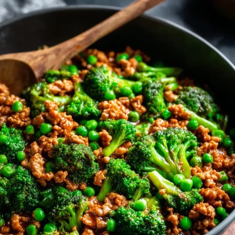 Una ollita negra con mezcla de carne, arvejas, brócoli y tomates.